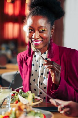 Parlak ceket ve pembe küpe giyen güzel şık kadın