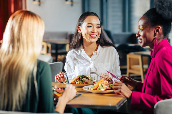 Three friends eating delicious salads in their favorite restaurant