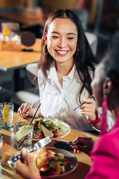 Сияющая деловая женщина наслаждается ужином со своими друзьями — стоковое фото