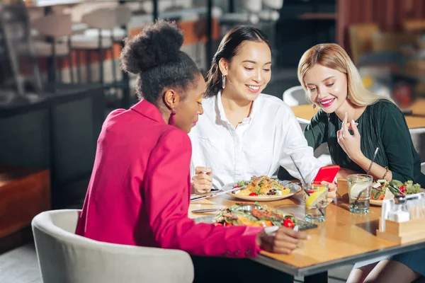 Três jovens mulheres comendo saladas saudáveis e assistindo vídeo — Fotografia de Stock