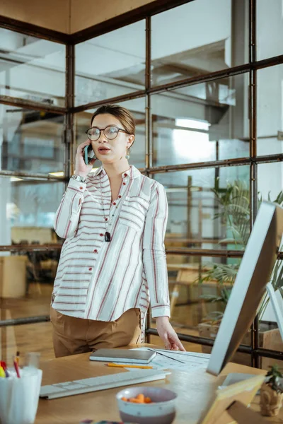 Pregnant businesswoman wearing glasses speaking by the phone