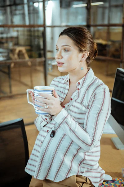 Беременная деловая женщина с большой белой чашкой во время чая — стоковое фото