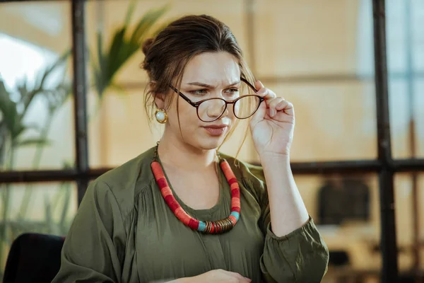 Young prosperous businesswoman putting her glasses on — Stock Photo, Image