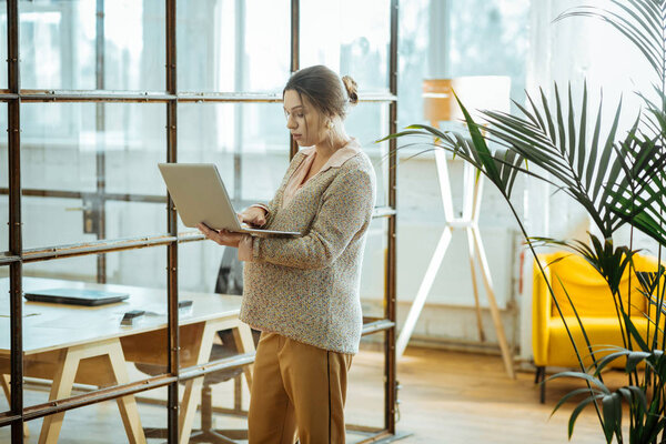 Pregnant successful businesswoman with hair bun holding laptop