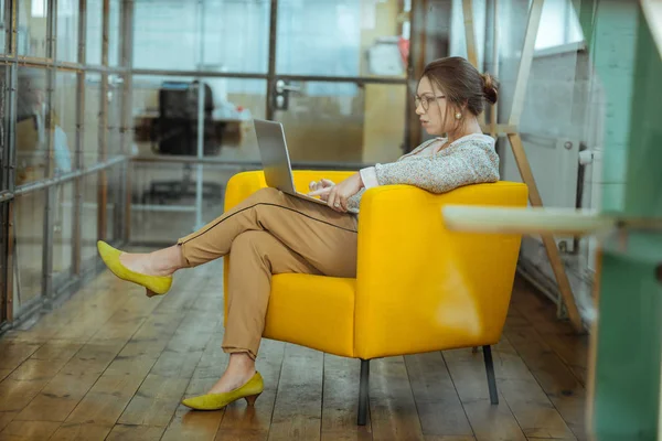 Mujer de negocios morena sentada en un cómodo sillón amarillo — Foto de Stock