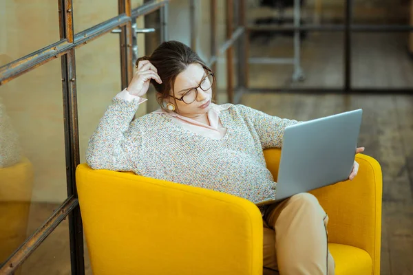 Empresária vestindo suéter e óculos enquanto trabalhava no laptop — Fotografia de Stock