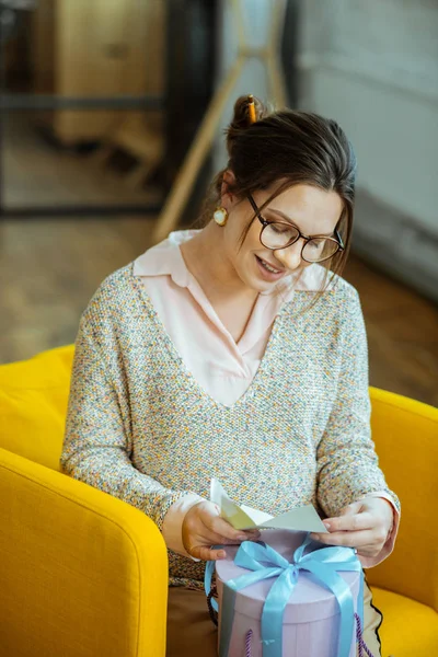 Mujer embarazada leyendo una pequeña carta después de recibir la caja presente — Foto de Stock