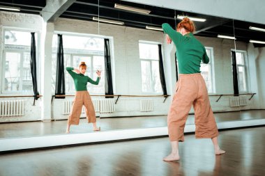 Bir dans okulu günde. Kızıl saçlı Genç dans öğretmeni arayan bir saç topuz ile onu gün stüdyoda harcama süre odaklı