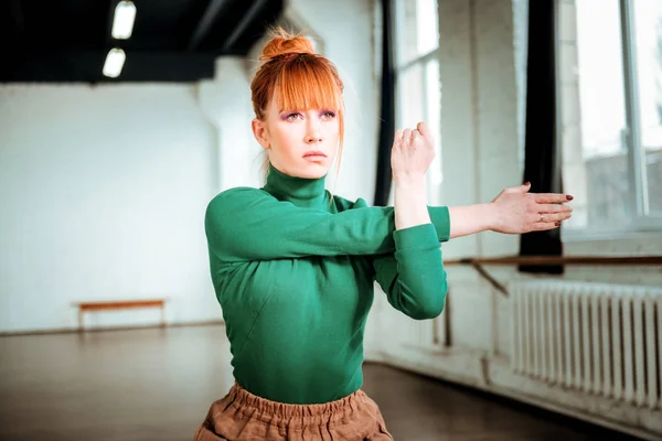 Pleasant-looking red haired girl in a turtleneck stretching her arms — Stock Photo, Image