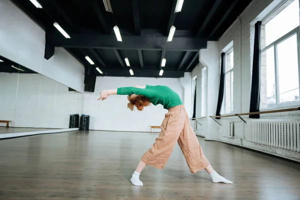 Pleasant-looking fit yoga instructor in a green turtleneck doing asana for back stretching — Stock Photo, Image