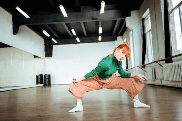 Bellissimo allenatore di yoga sottile in un dolcevita verde che fa asana per gambe forti — Foto Stock