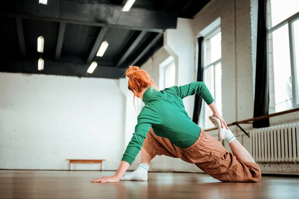 Allenatore di yoga professionale con un panino per capelli che si estende la gamba — Foto Stock