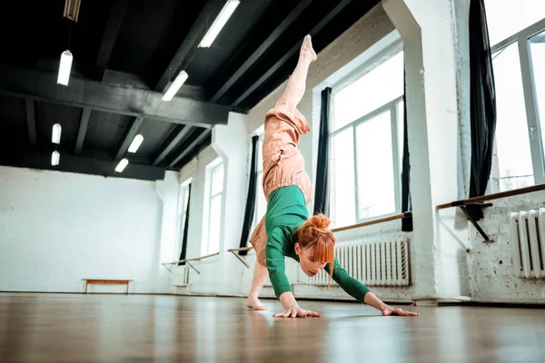 Professionele yoga coach met een broodje van de haren doen een stand op haar handen — Stockfoto