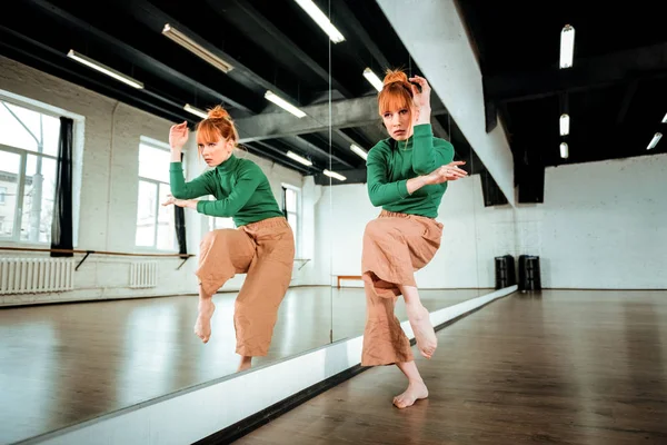 Mooie professionele moderne danseres met rode haren dansen in de buurt van de spiegel — Stockfoto