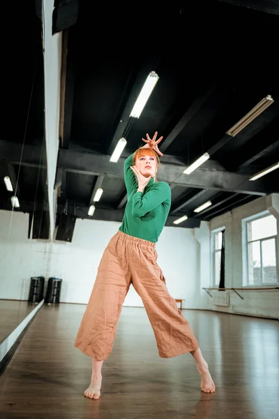 Red-haired professional dance teacher dancing in the studio