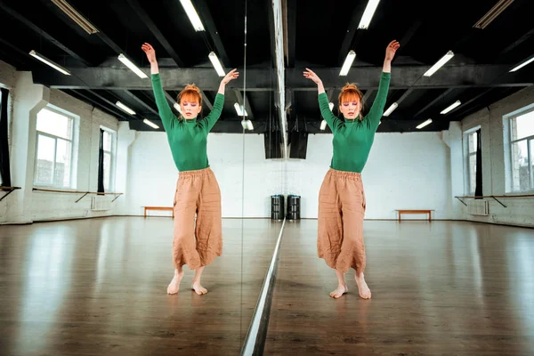 Leuk roodharige dansleraar in een groene coltrui verhogen haar handen — Stockfoto