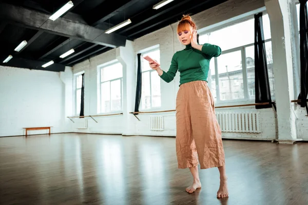 Red-haired professional yoga instructor with hair bun listening carefully