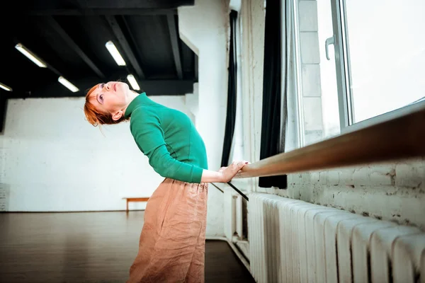 Jovem bailarina profissional de balé com coque de cabelo fazendo arqueamento — Fotografia de Stock