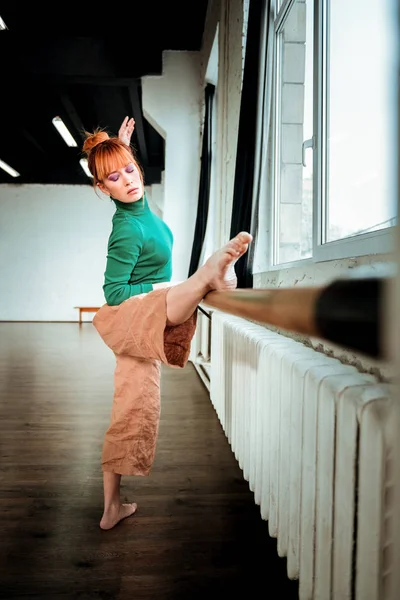 Jonge professionele balletdanser met haar broodje doen benen rekken — Stockfoto