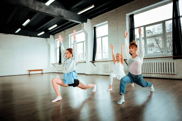 Slim belle prof de ballet et ses élèves levant la main vers le haut — Photo