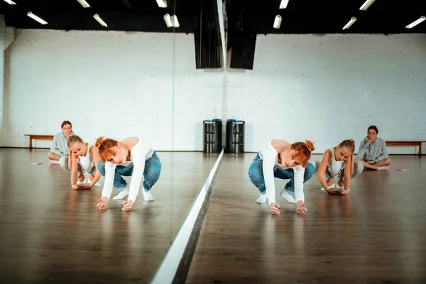 Roodharige ballet leraar in spijkerbroek bewegingen tonen aan haar studenten — Stockfoto