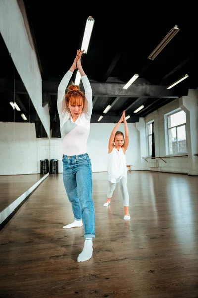 Red-haired ballet teacher and her student raising their hands in the air