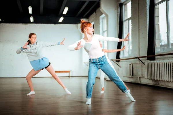 Roodharige dansleraar in spijkerbroek en haar studenten actief dansen — Stockfoto