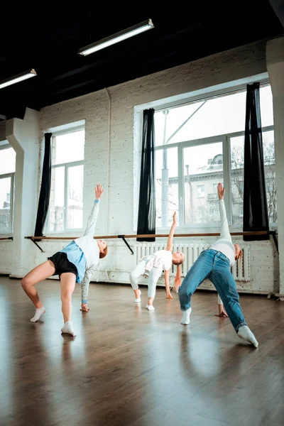 Profesora de danza pelirroja en vaqueros azules y sus estudiantes buscando flexible —  Fotos de Stock