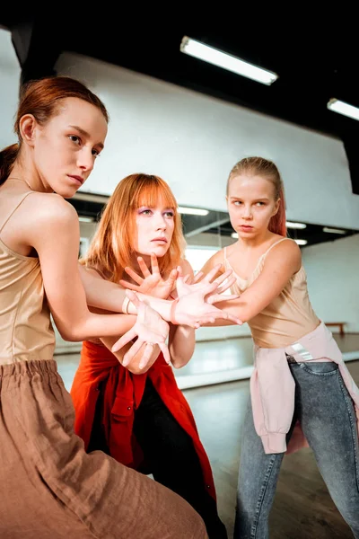 Beautiful dance teacher with red hair and her students doing arm stretching