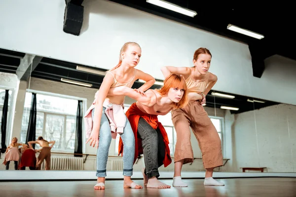 Schöne Tanzlehrerin mit roten Haaren und ihren Schülern, die ihre Beine strecken — Stockfoto