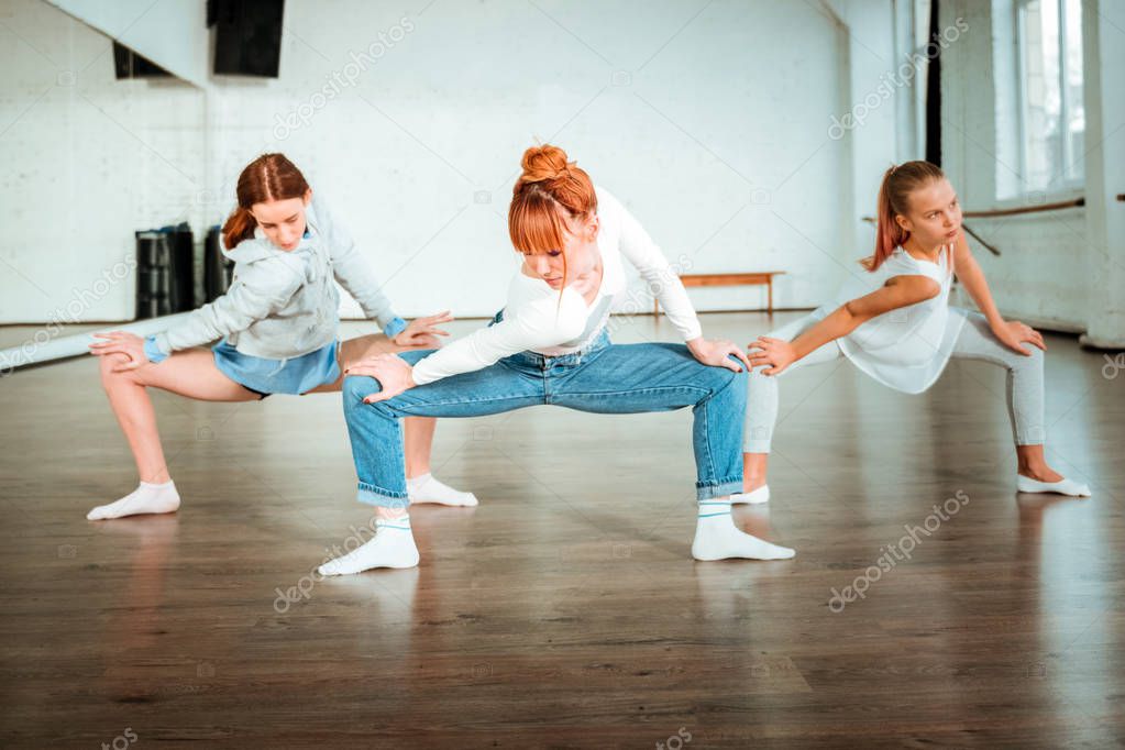 Slim beautiful ballet teacher showing shoulders movements to her students