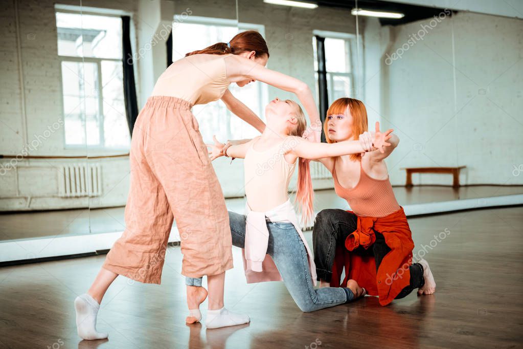 Two students of a dance school and their teacher feeling concentrated