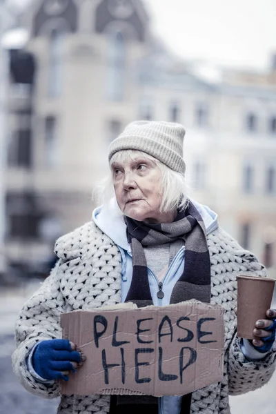 Депрессивная старшая женщина попрошайничает на улице — стоковое фото