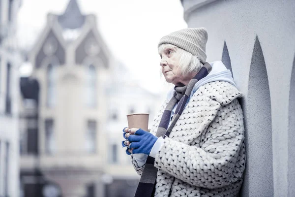 Sad aged woman standing at the corner of a building — Stock Photo, Image