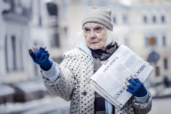 Donna anziana infelice che vende giornali alla gente — Foto Stock