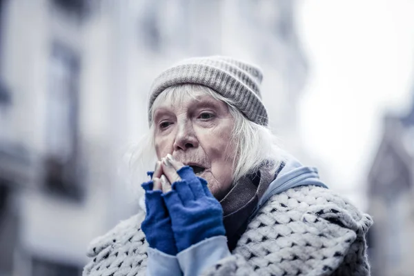 Mulher idosa triste tentando aquecer as mãos — Fotografia de Stock