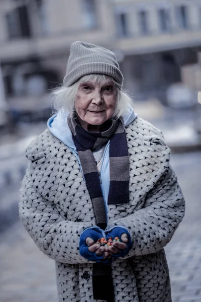 Positive poor woman holding handful of sweets