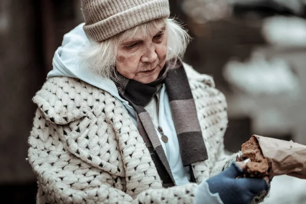 Сумна літня жінка бере шматочок хліба — стокове фото