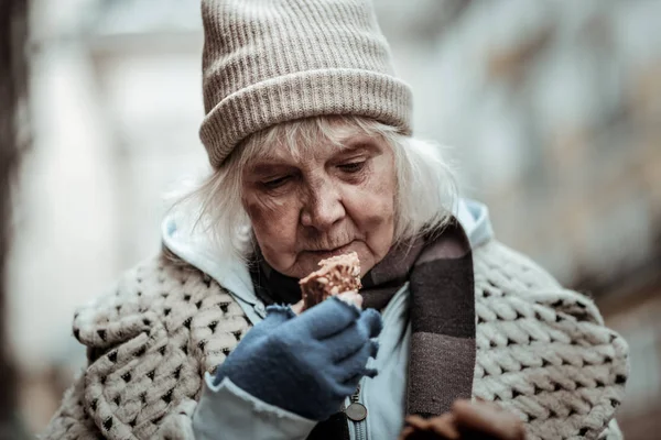Mulher idosa agradável olhando para o pão — Fotografia de Stock