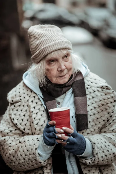 Depressed homeless woman standing with a cup of tea — Stock Photo, Image