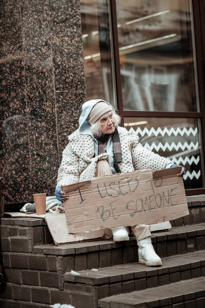 Cheerless senior woman sitting on the stairs
