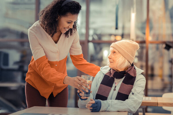 Delighted young woman bringing a glass of water