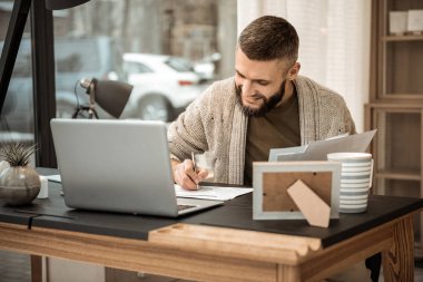 Gülümseyen pozitif iş adamı gri hırka toplantı aşağı yazma içinde