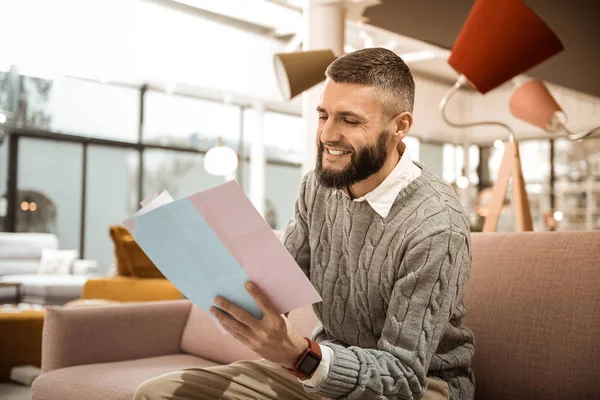 Laughing bearded man looking for needed furniture — Stock Photo, Image