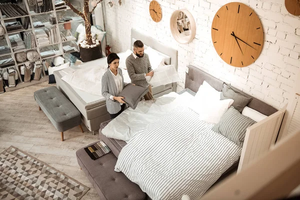 Konzentriertes Paar beobachtet Bett und Kissen im Komplex — Stockfoto
