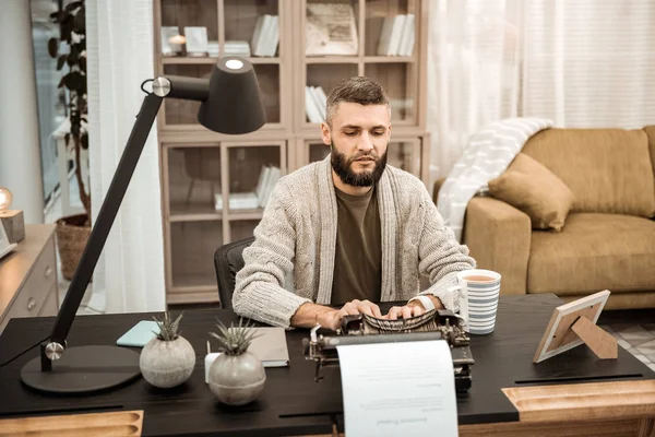 Homem sério concentrado em cardigan cinza digitando na máquina de escrever — Fotografia de Stock