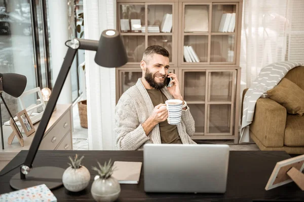 Glad positiv man pratar i mobiltelefon och dricka varm te — Stockfoto