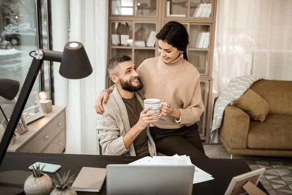 Joyful casal positivo abraçando uns aos outros e compartilhando chá quente — Fotografia de Stock