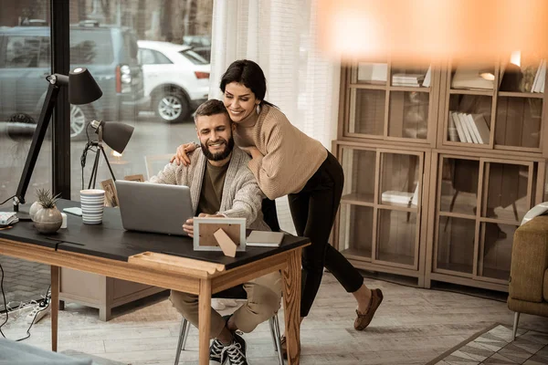 Attraktive langhaarige Frau, die sanft mit ihrem arbeitenden Mann umgeht — Stockfoto