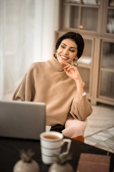 Calm peaceful attractive woman spending time with her laptop